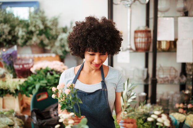 Afrikanischer weiblicher Florist des Afro, der Blumen im Shop anordnet