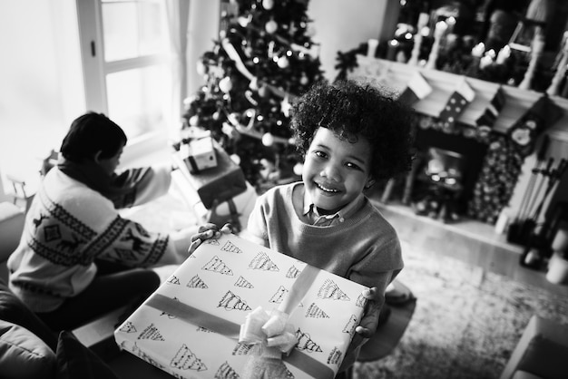 Kostenloses Foto afrikanisches kind, das ein weihnachtsgeschenk hält