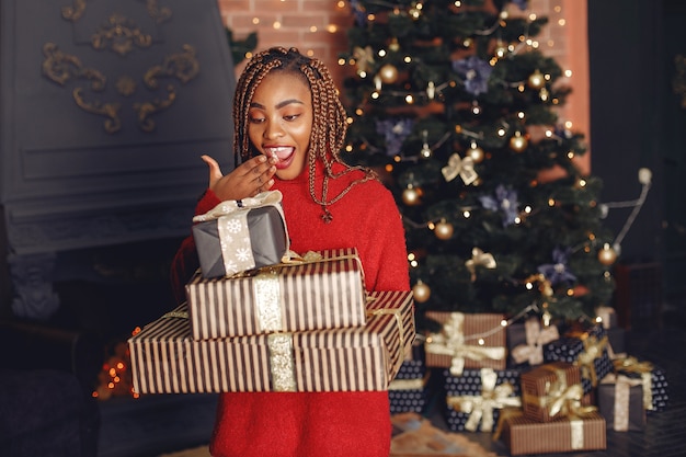 Afrikanisches Mädchen in einer Weihnachtsdekoration / Frau in einem roten Pullover. Neujahrskonzept.