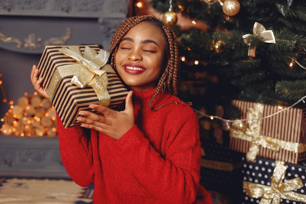 Afrikanisches Mädchen in einer Weihnachtsdekoration / Frau in einem roten Pullover. Neujahrskonzept.