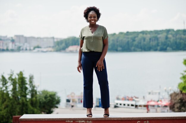 Afrikanisches Mädchen posierte auf der Straße der Stadtkleidung auf grüner Bluse und blauer Hose