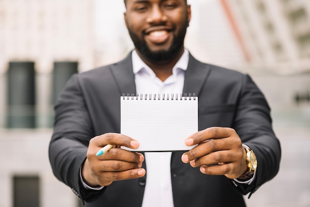 Kostenloses Foto afro-amerikanischer mann, der leeres notizbuch hält