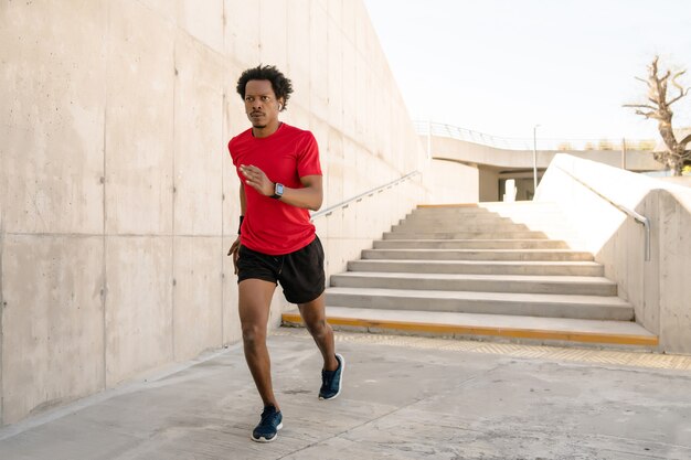 Afro athletischer Mann, der draußen auf der Straße läuft und Übung macht