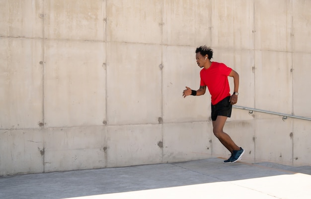 Afro athletischer Mann, der draußen auf der Straße läuft und Übung macht
