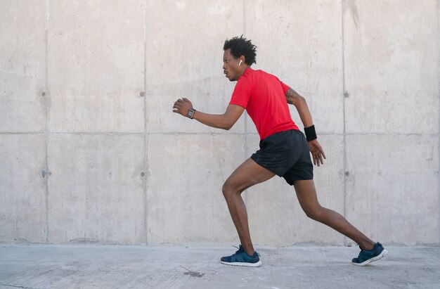 Afro athletischer Mann, der draußen auf der Straße läuft und Übung macht