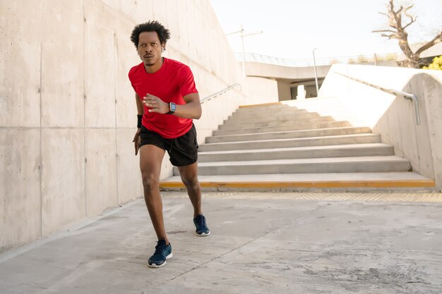 Afro athletischer Mann, der draußen auf der Straße läuft und trainiert. Sport und gesundes Lifestyle-Konzept.
