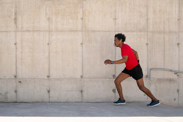 Afro athletischer Mann, der draußen auf der Straße läuft und trainiert. Sport und gesundes Lifestyle-Konzept.