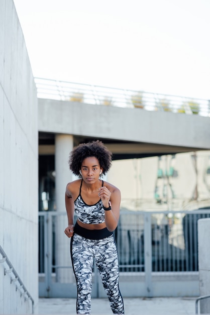 Afro sportliche Frau läuft und macht Übung im Freien