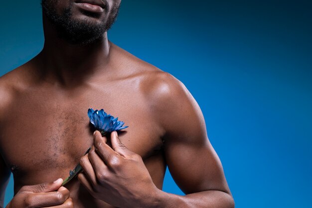 Afroamerikaner, der eine blaue Blume hält
