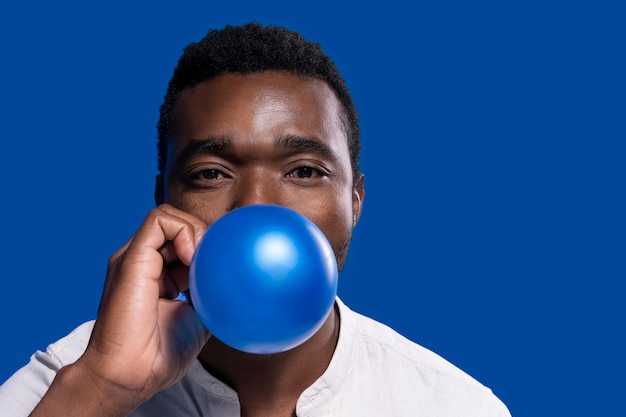 Afroamerikaner, der einen blauen Ballon hält