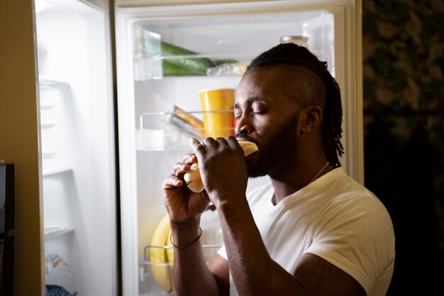 Afroamerikaner, der nachts aus dem Kühlschrank isst