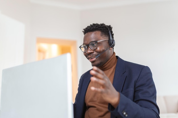 Afroamerikaner mit Kopfhörern, der gute Nachrichten in E-Mails liest und neue Stellenangebote mit Laptop erhält