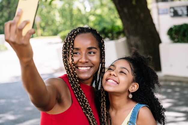 Afroamerikaner Mutter und Tochter genießen einen Tag im Freien, während sie ein Selfie mit einem Mobiltelefon auf der Straße machen