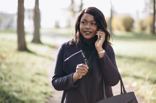 Afroamerikanerfrau, die am Telefon im Park spricht