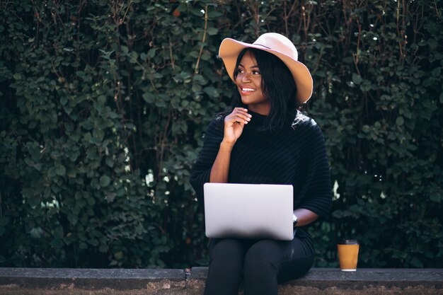 Afroamerikanerfrau, die draußen an einem Computer arbeitet