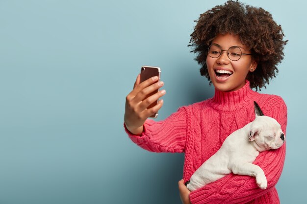 Afroamerikanerfrau, die rosa Pullover hält Hund hält