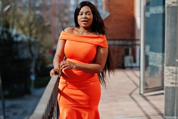 Afroamerikanerfrauenmodell xxl im orangefarbenen Kleid