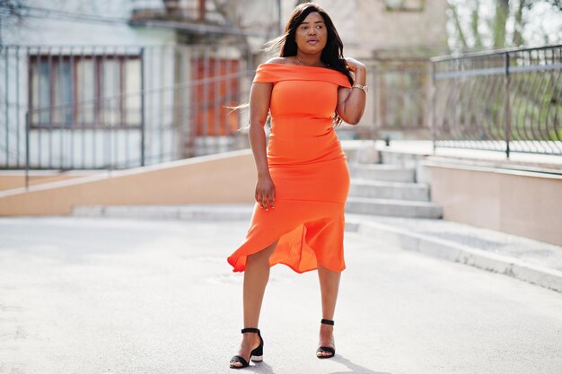 Afroamerikanerfrauenmodell xxl im orangefarbenen Kleid