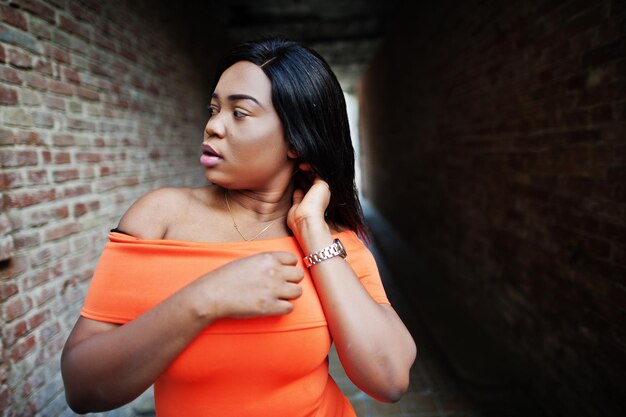 Afroamerikanerfrauenmodell xxl im orangefarbenen Kleid