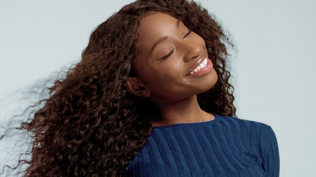 Afroamerikanerfrauenporträt der Schönheitsmischrasse im rosa Hintergrund mit Wind im Haar auf Blau