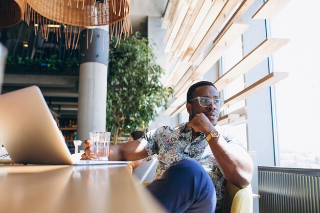 AfroamerikanerGeschäftsmann, der mit Laptop in einem Café arbeitet