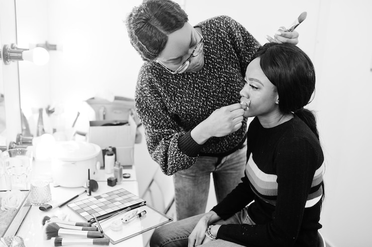 Kostenlose Foto afroamerikanerin beim schminken durch maskenbildner im schönheitssalon