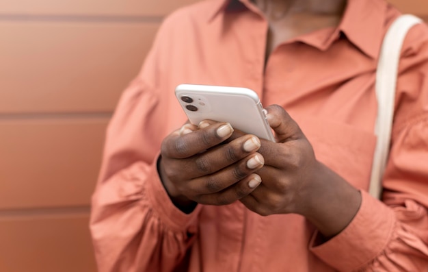 Afroamerikanerin, die jemandem auf ihrem Smartphone eine SMS schreibt