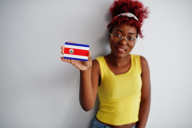 Kostenloses Foto afroamerikanerin mit afro-haar trägt gelbes unterhemd und brille und hält die costa-rica-flagge isoliert auf weißem hintergrund