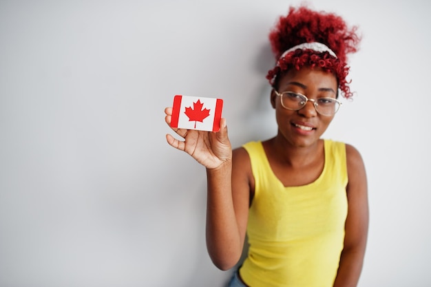 Afroamerikanerin mit Afro-Haar trägt gelbes Unterhemd und Brille und hält Kanada-Flagge isoliert auf weißem Hintergrund