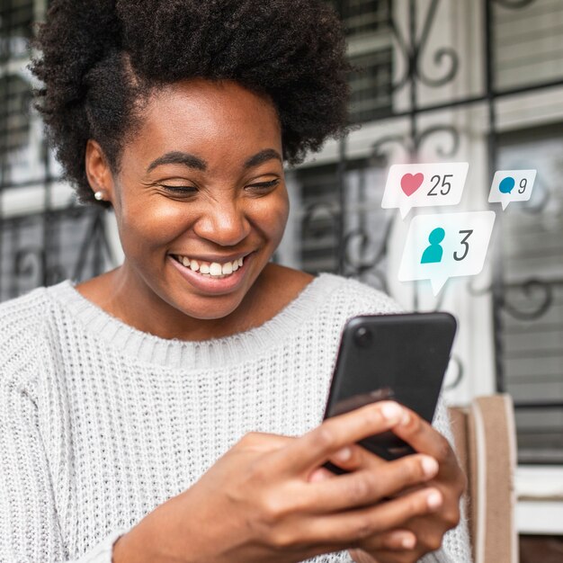 Afroamerikanerin überprüft Social Media auf einem Telefon