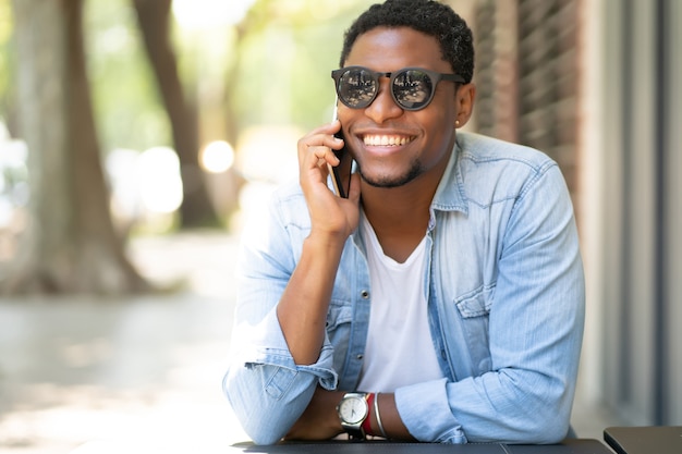 Afroamerikanermann, der am Telefon spricht, während er am Kaffeehaus sitzt