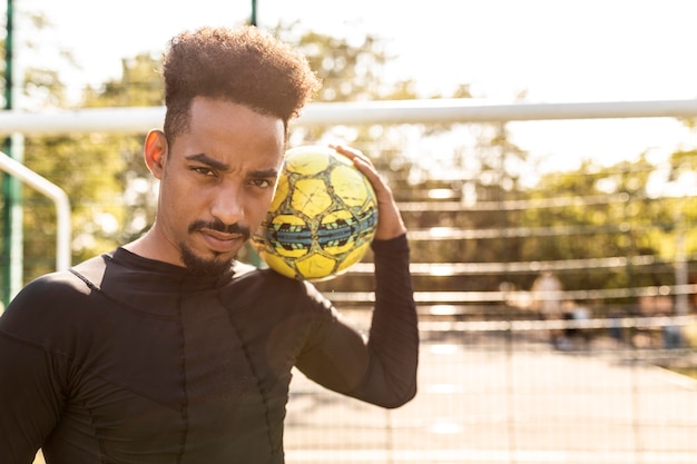 Kostenloses Foto afroamerikanermann, der mit einem fußball draußen spielt