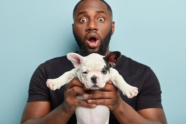 Afroamerikanermann, der schwarzen T-Shirt hält Hund hält