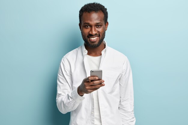 Afroamerikanermann, der weißes Hemd hält Telefon hält