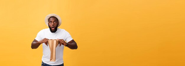 Afroamerikanermann mit den bunten Papiertüten lokalisiert auf gelbem Hintergrund