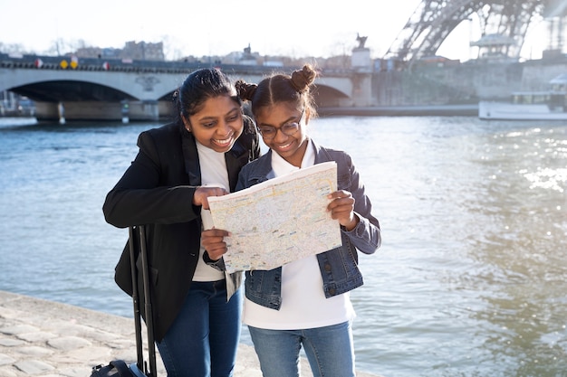 Afroamerikanermutter und -tochter, die die karte in ihrer reise nach paris beobachten