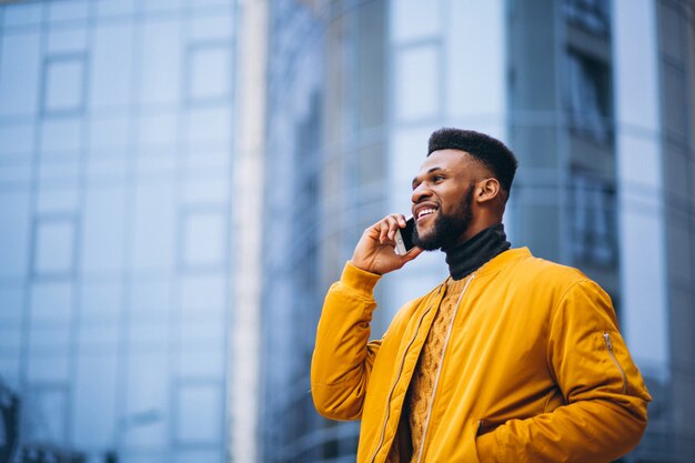 Afroamerikanerstudent, der in die Straße geht und am Telefon spricht