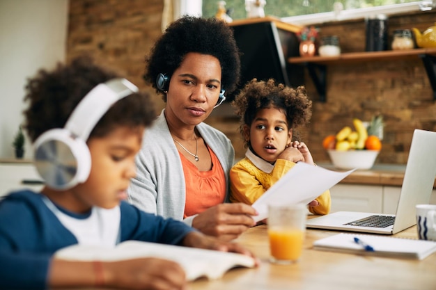 Afroamerikanische alleinerziehende Mutter mit zwei Kindern, die zu Hause arbeiten