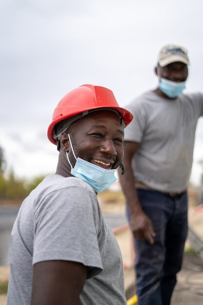 Afroamerikanische Bauarbeiter, die bei der Arbeit Helme und Gesichtsmasken tragen