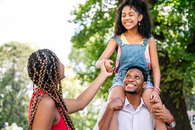 Afroamerikanische Familie, die Spaß hat und gute Zeit zusammen verbringt, während sie draußen auf der Straße spazieren geht.