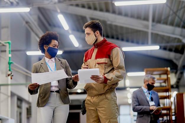 Afroamerikanische geschäftsfrau im gespräch mit einem arbeiter in einer holzverarbeitenden industrieanlage