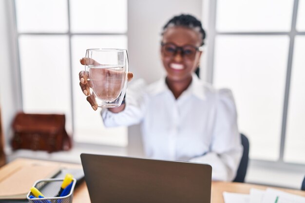 Afroamerikanische Geschäftsfrau mit Laptop-Trinkwasser im Büro