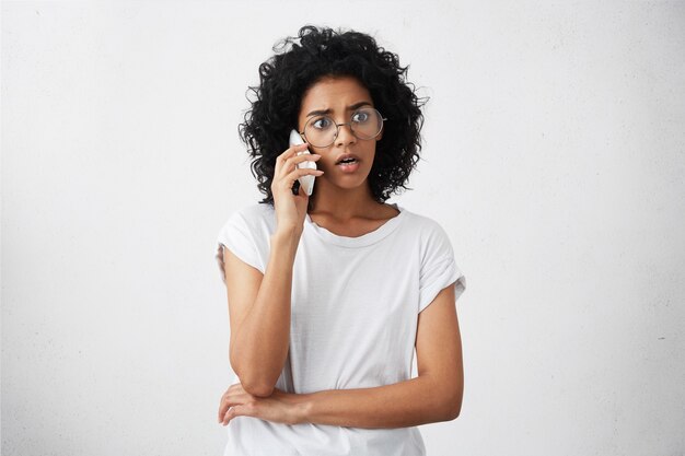 Afroamerikanische Hausfrau mit lockigem Haar, großer runder Brille und lässigem T-Shirt