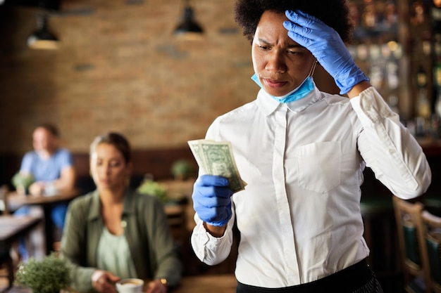 Afroamerikanische Kellnerin, die mit einem Trinkgeld eines Kunden in einem Café unzufrieden ist