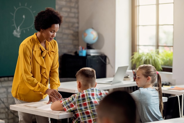 Afroamerikanische Lehrerin hilft ihren Schülern in einer Grundschulklasse