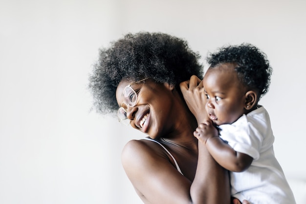 Afroamerikanische Mutter kümmert sich und liebt ihr Baby vor einem weißen Hintergrund