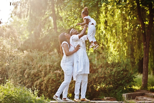 Afroamerikanische reiche Familie, die sich bei Sonnenuntergang amüsiert Vater wirft Tochter auf seine Hände