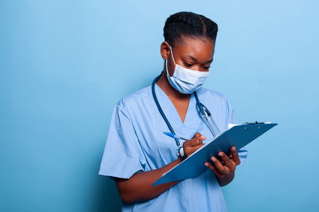 Afroamerikanische Therapeutenkrankenschwester, die eine schützende medizinische Gesichtsmaske gegen Coronavirus trägt