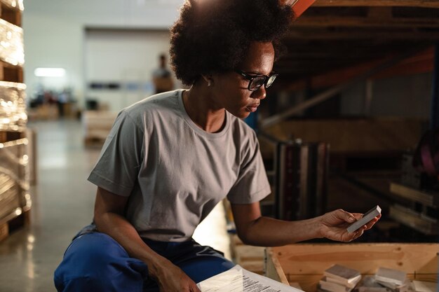 Afroamerikanischer Arbeiter, der hergestellte Stahlfliesen analysiert, während er in einem industriellen Lagerraum arbeitet