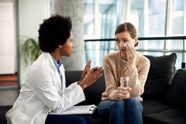 Afroamerikanischer Berater im Gespräch mit einer weinenden Frau während einer Psychotherapiesitzung